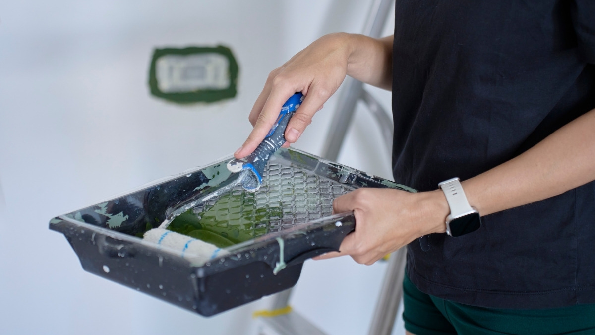 a person holding a black plastic paint tray