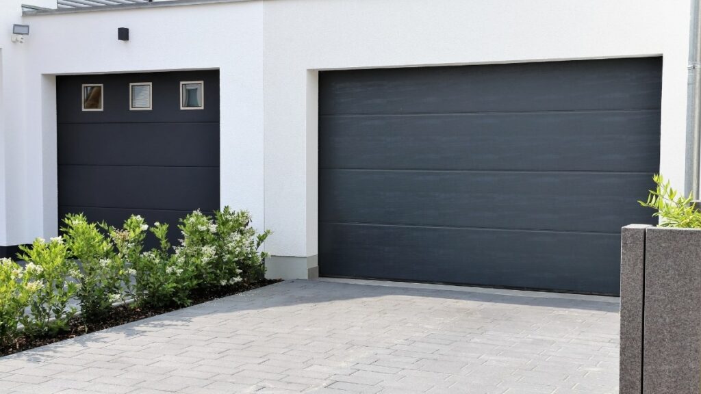 modern residential exterior featuring two dark charcoal grey minimalist garage doors